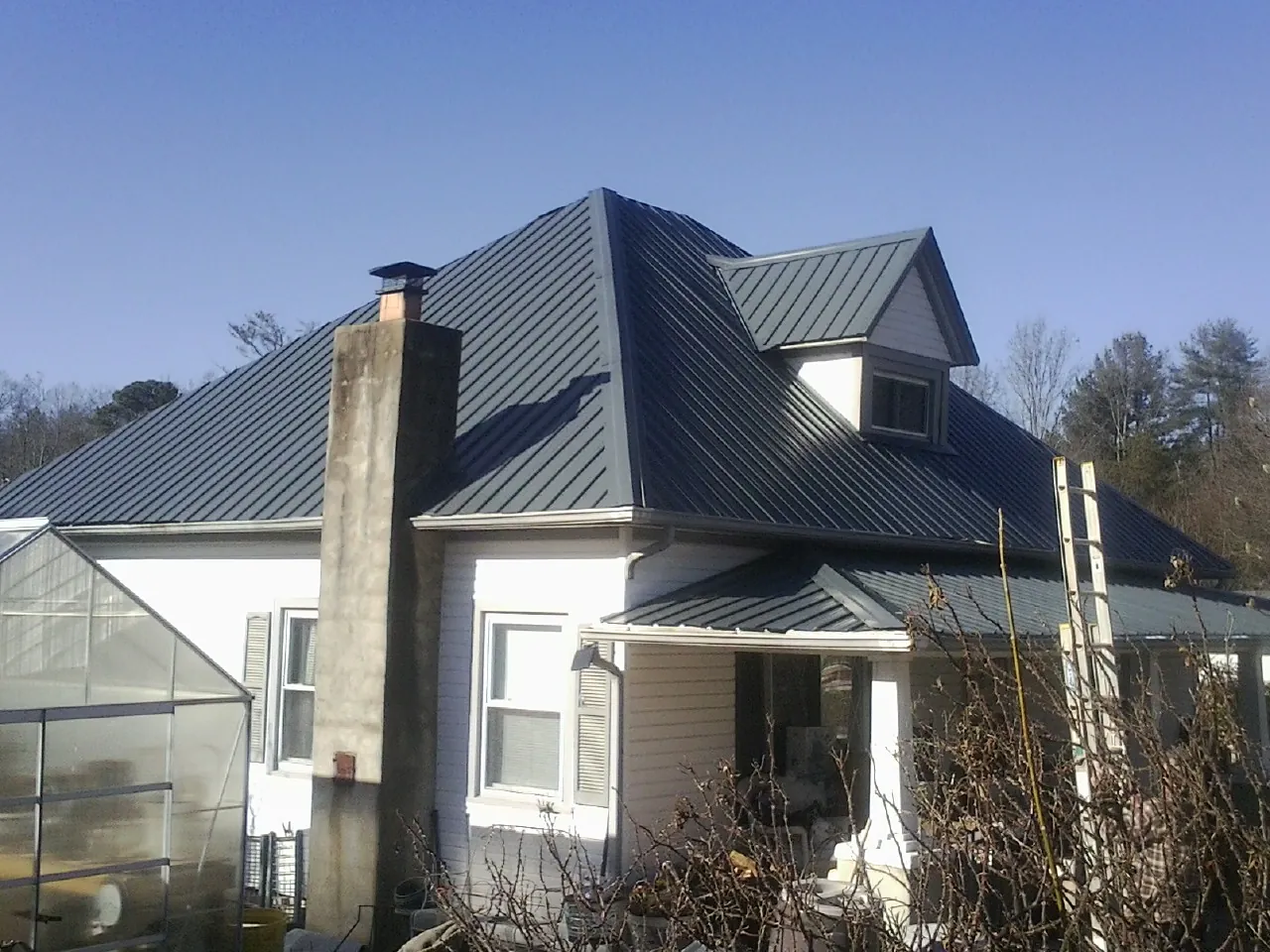 Dark blue standing seam metal roof on a white farmhouse with dormer — Slate & Tile Roof Repair by Roofing Brothers in Franklin